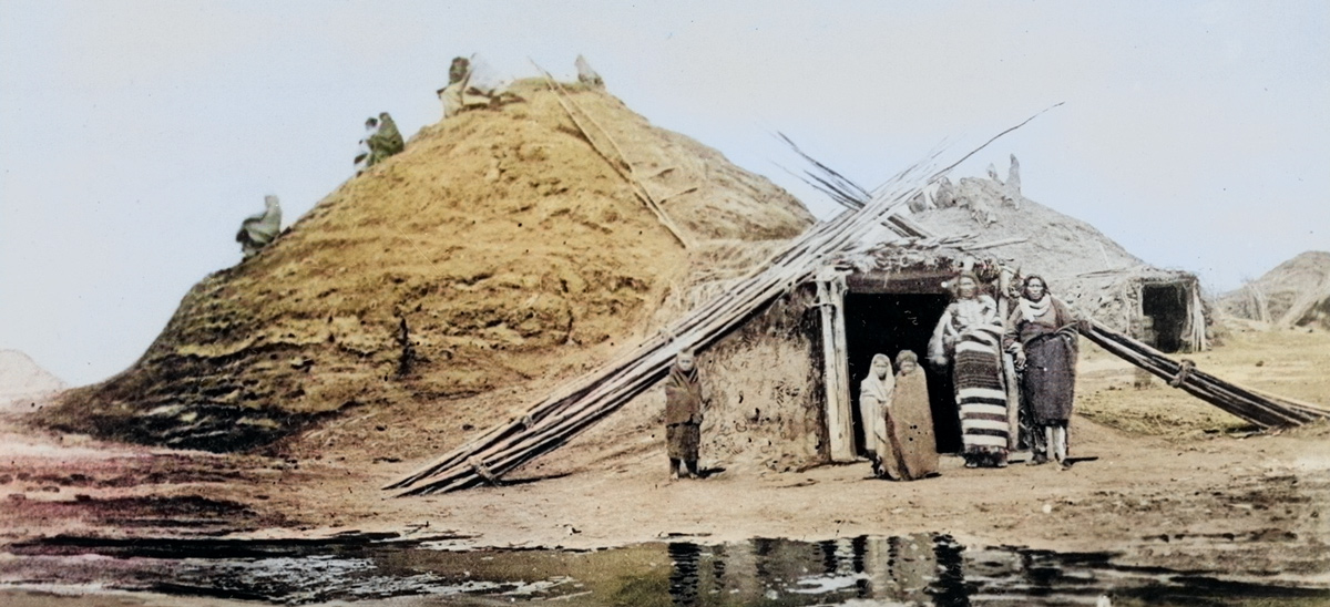 A Pawnee family stands in front of a large mud lodge