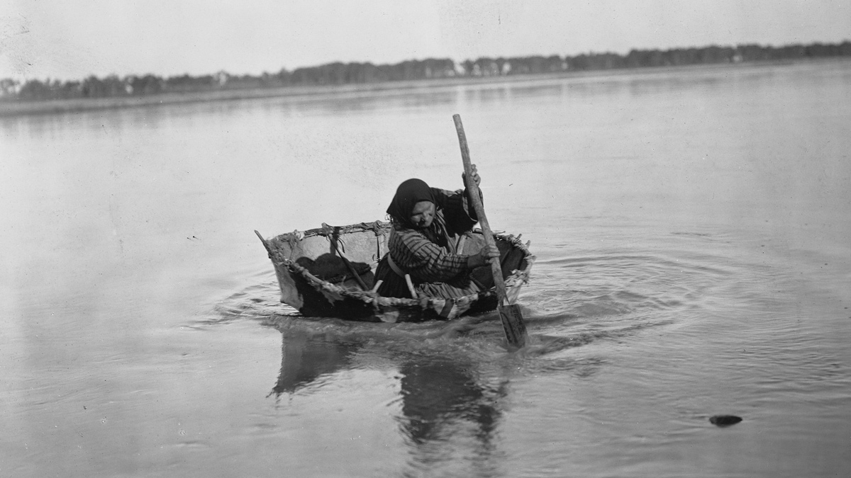 Historic photo of an Indian women paddling a small round boat
