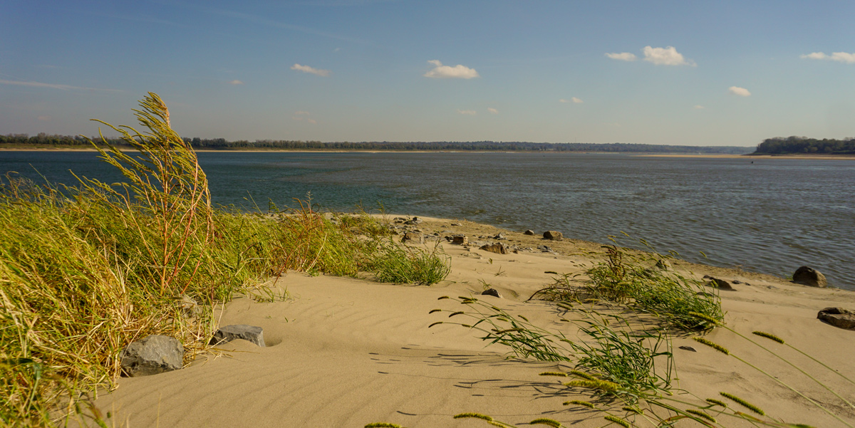 A sandy spit juts out into a wide body of water