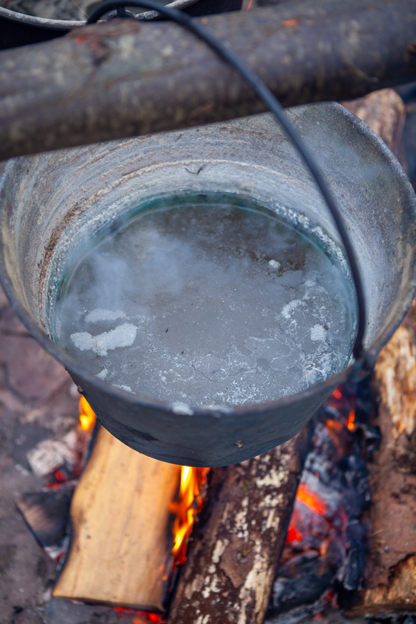 A kettle of salt brine boils over an open fire